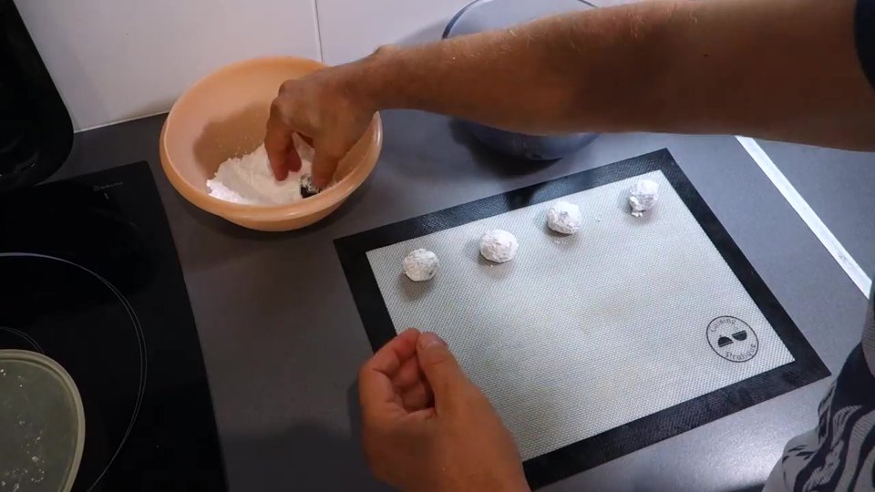 Boules de pâte à craquelés roulées dans le sucre glace.