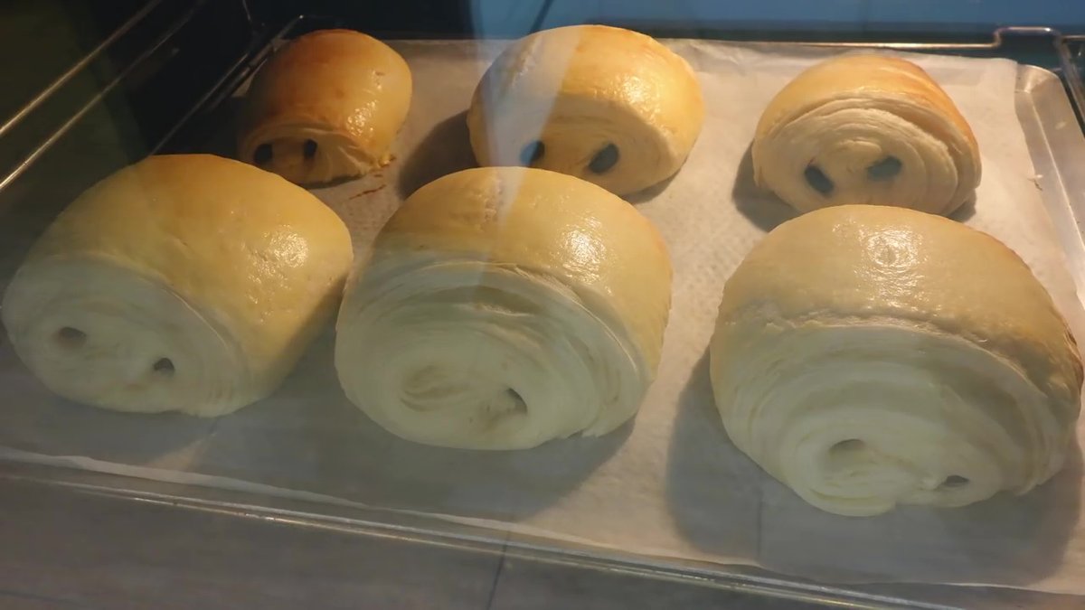 Pains au chocolat maison en cuisson au four après pousse, dorés et gonflés.