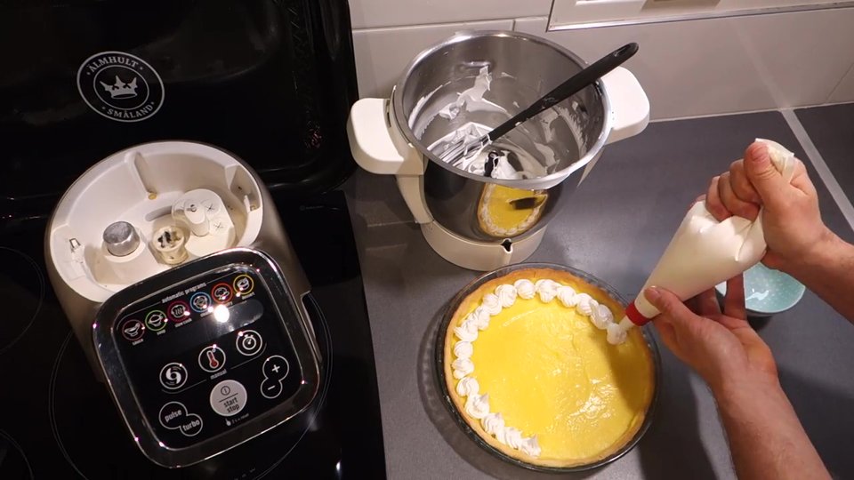 Dressage de la meringue italienne à la poche à douille sur une tarte pour une finition pâtissière.